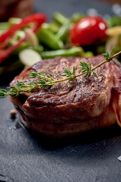 Filet mignon steak met groente garnituur op een zwart bord. Close-up, selectieve focus