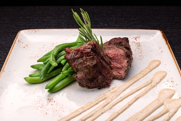 Filet mignon with asparagus on a light plate on a dark background