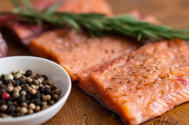 Filet van rode vis met rozemarijn voor steaks op snijplank naast pot met kruidenSelectieve focus