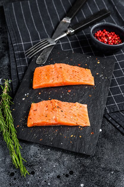 Filet zalm steak op een stenen bord. Zwart oppervlak. Bovenaanzicht