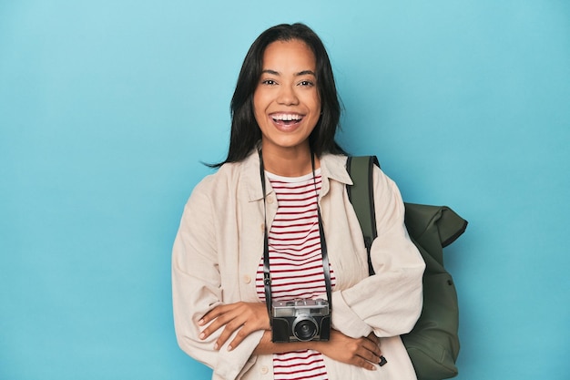 Filipina woman with camera and backpack on bluelaughing and having fun