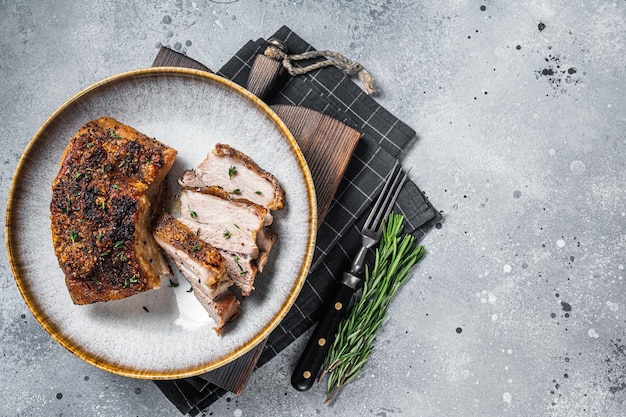 Filipino marinated pork belly with crust in a plate. Gray background. Top view. Copy space.