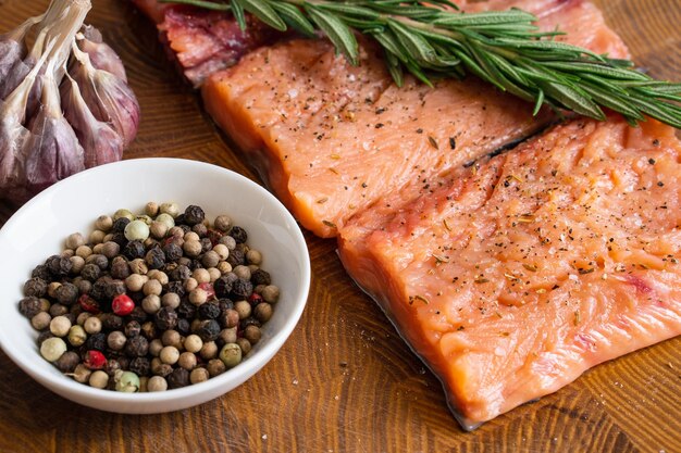 Fillet of red fish with rosemary for steaks on cutting board next to jar with spicesSelective focus