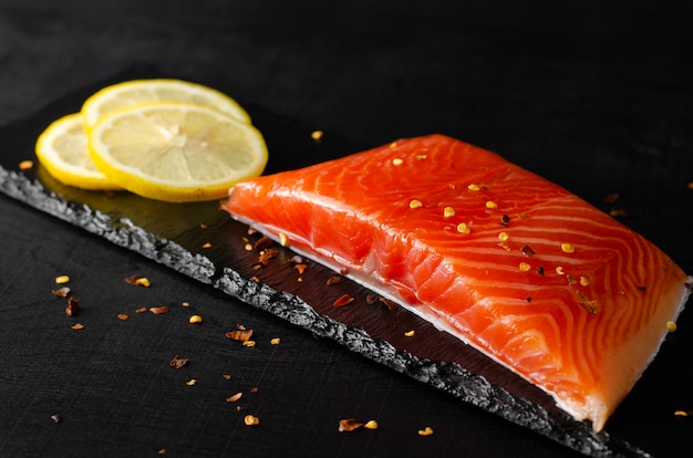 Fillet of salmon and lemon slices on black 