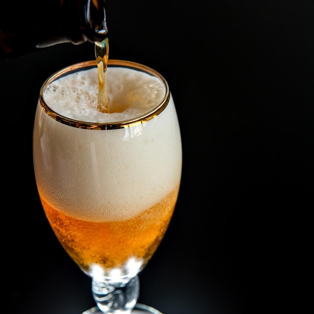 Filling beer glass on black background