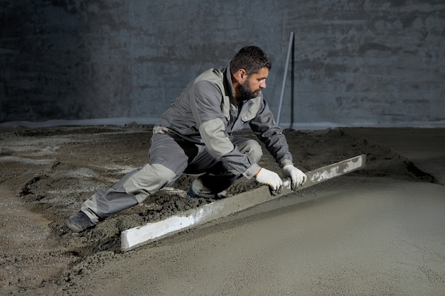 Filling the floor with concrete, screed and leveling floor by construction workers