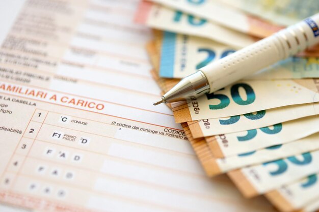 Filling italian tax form process with pen and euro money bills close up tax paying period
