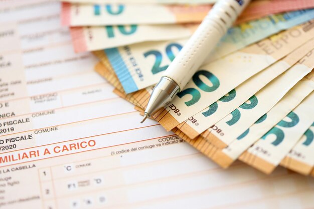 Filling italian tax form process with pen and euro money bills close up tax paying period