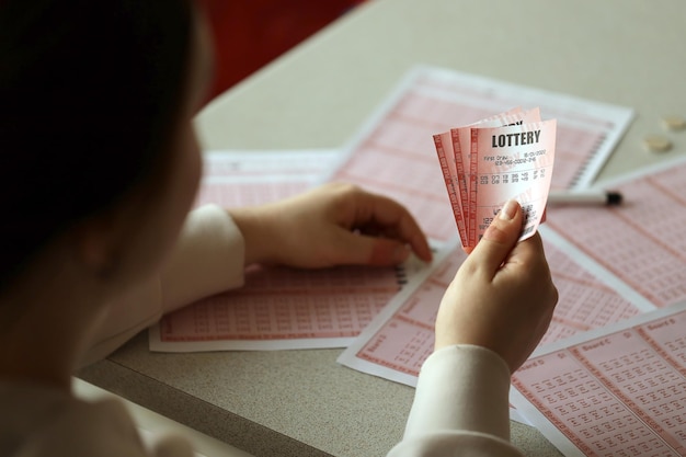 Filling out a lottery ticket A young woman holds the lottery ticket with complete row of numbers on the lottery blank sheets background