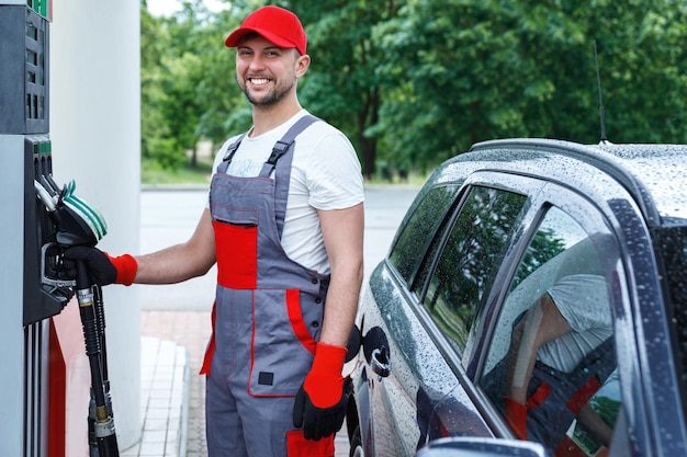 Foto addetto alla stazione di servizio con un ugello di carburante tra le mani che riempie il serbatoio dell'auto del cliente