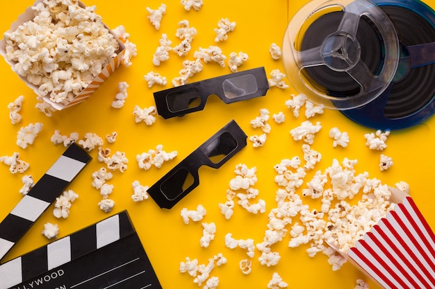 Film achtergrond. Filmklapper, filmrol, popcorn en 3D-bril op gele achtergrond, kopieerruimte, bovenaanzicht