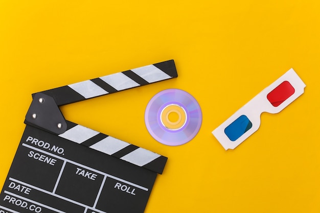 Film clapper board, 3d glasses and cd on yellow background. Cinema industry, entertainment. Top view