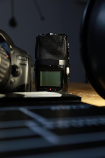 Film clapper with a camera, a microphone and a VHS tape on wood.