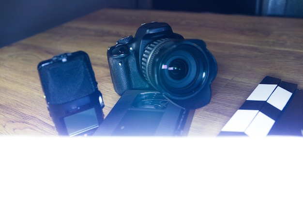 Photo film clapper with a camera, a microphone and a vhs tape on wood.