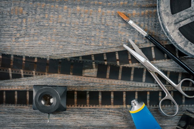 Film, scissors, glue and a brush mounting negatives lie on an old wooden table