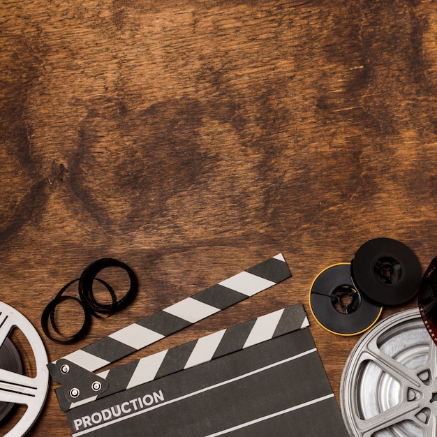 Photo film stripes; film reel and clapperboard on wooden desk