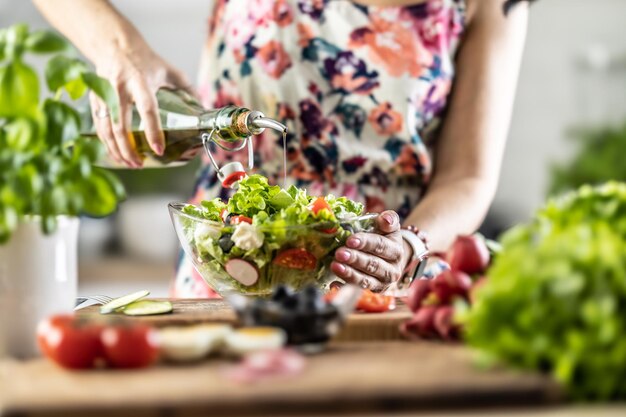 The final preparation of a healthy salad and at the end the woman pours olive oil