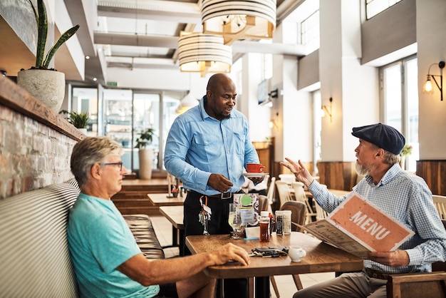 Finally my coffee is here Shot of two senior friends placing an order with a waiter at their favorite cafe