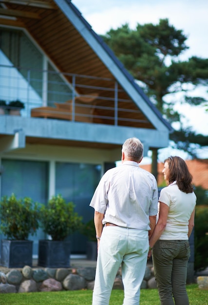 Finally we can afford our dream home Rearview shot of a mature couple standing handinhand in front of their home