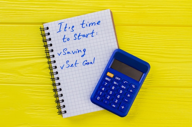 Finance and accounting concept. Calculator with notepad on yellow wood.