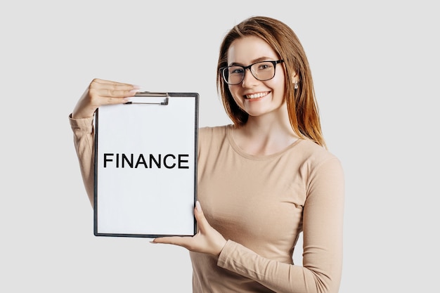 FINANCE. Beautiful young business woman wearing glasses holds a clipboard with mock up space isolated on gray background