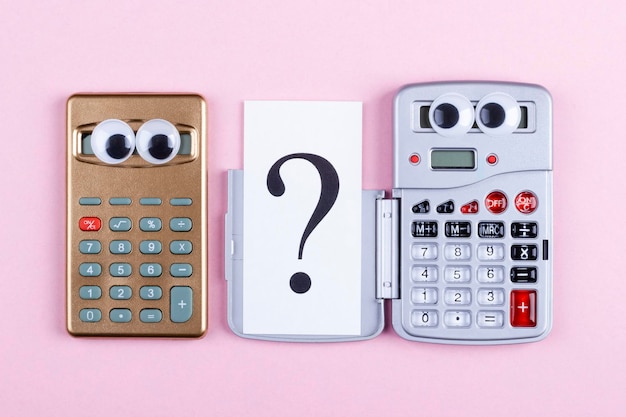 Finance and business concept Question mark and two unusual calculators on a pink background closeup