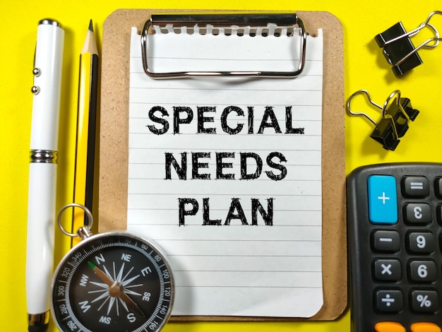 Finance conceptText SPECIAL NEEDS PLAN writing on clip board with penpencilpaper clipscompass and calculator on yellow background