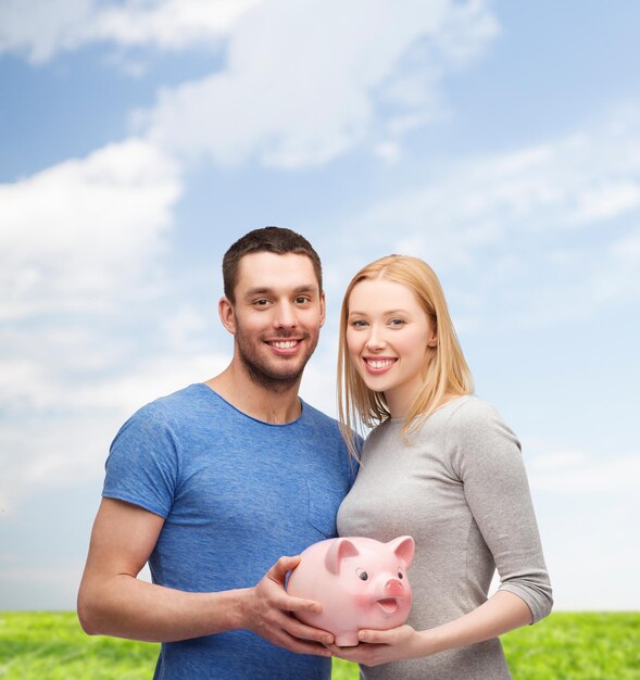 finance, money and family concept - smiling couple holding big piggy bank