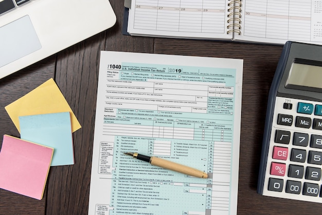 Finance tax form with calculator, laptop and pen