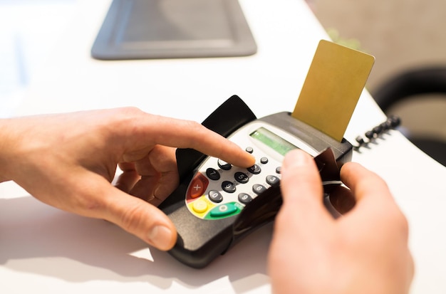 finance, technology, payment , money and people concept - close up of hand entering pin code to bank terminal with credit car