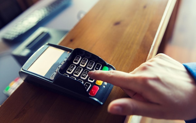 finance, technology, payment and people concept - close up of hand entering pin code to money terminal