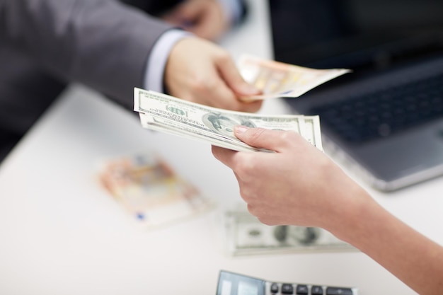 finances, currency, exchange rate, business and people concept - close up of male and female hands giving or exchanging money at office