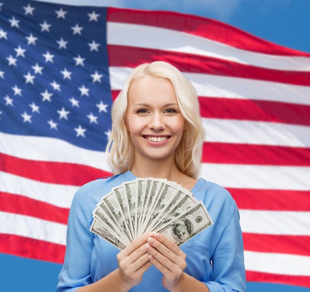 finances and people concept - smiling woman in red dress with us dollar money over american flag background