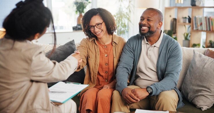 Photo financial advisor handshake and mature couple on sofa for estate planning asset management or pension documents life insurance and retirement fund with people at home for investment portfolio