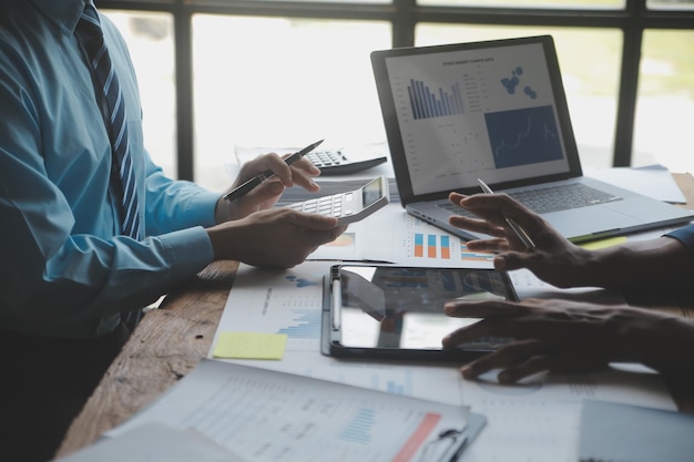 Financial analysts analyze business financial reports on a digital tablet planning investment project during a discussion at a meeting of corporate showing the results of their successful teamwork