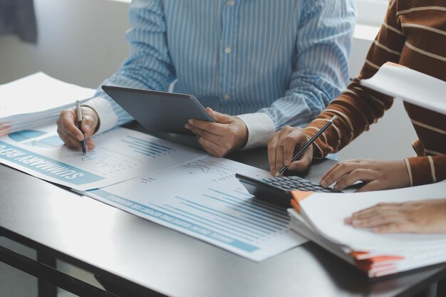 Financial analysts analyze business financial reports on a digital tablet planning investment project during a discussion at a meeting of corporate showing the results of their successful teamwork