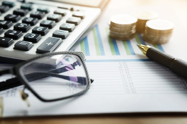 Фото Финансовые графики на столе с ноутбуком, калькулятор, ручка и очки бизнес-концепция