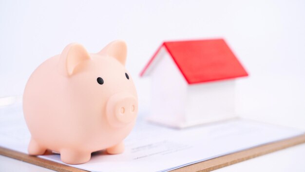 Financial concpet Piggy bank beautiful red white wooden house model on white background saving money to buy insurance close up copy space