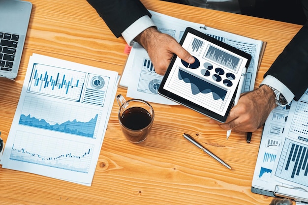 フィンテックBIまたはビジネスインテリジェンスによる財務データ分析ダッシュボードは,タブレット画面で表示され,ビジネスマンがテーブル上でマーケティングを計画するための財務データ分析を深めます.