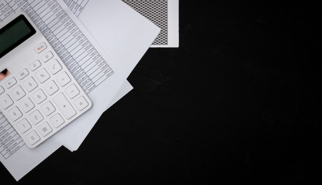 Фото Финансовые документы и белые калькуляторы на черных деревянных столах