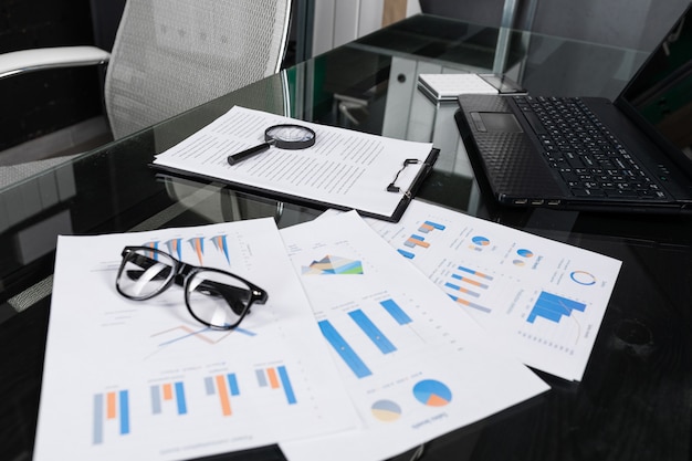 Financial documents with magnifying glass and insurance lie on black table in office close-up