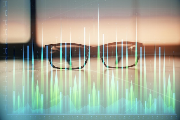 Financial graph hologram with glasses on the table background Concept of business Double exposure