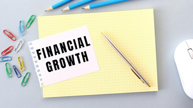 Crescita finanziaria è scritto su un pezzo di carta che giace su un quaderno accanto alle forniture per ufficio.
