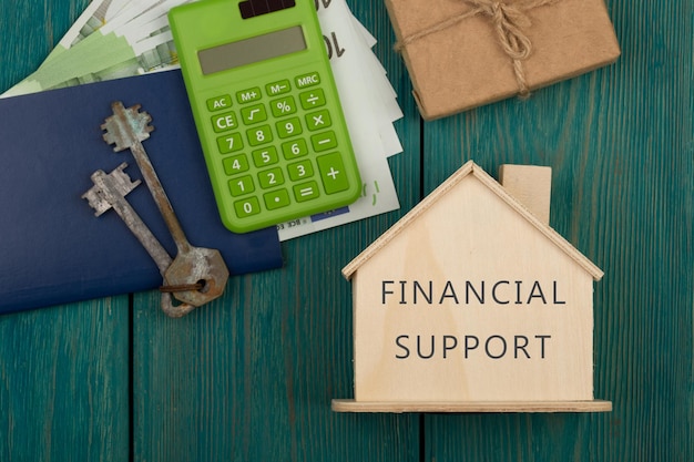 Financial helping concept little house with text Financial support keys calculator passport money