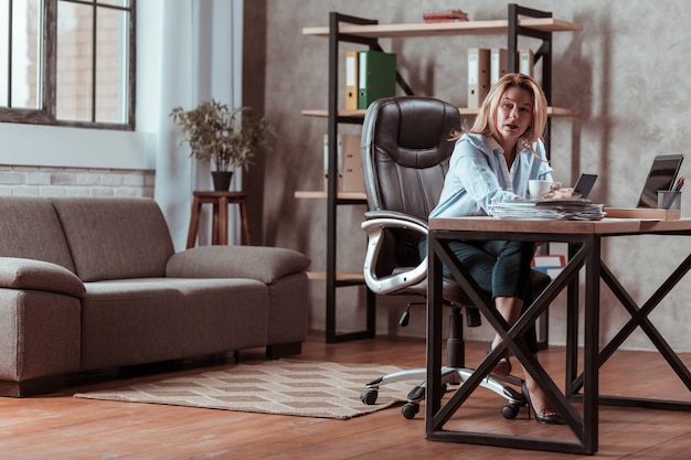 Financial issues. Blonde-haired stylish businesswoman feeling concerned about some financial issues