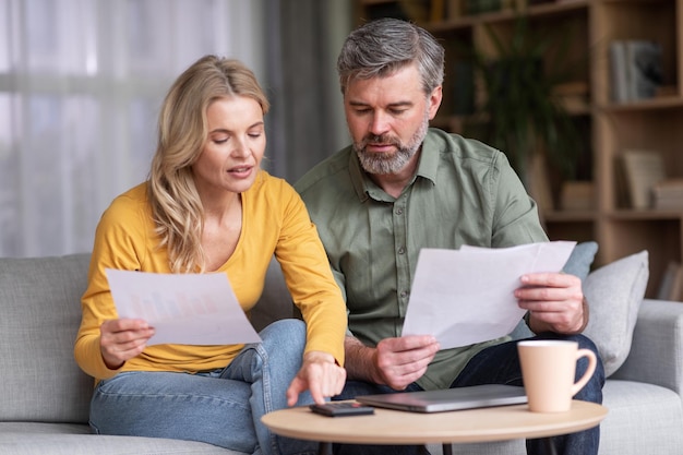 Foto alfabetizzazione finanziaria marito e moglie di mezza età occupati che calcolano insieme il bilancio familiare