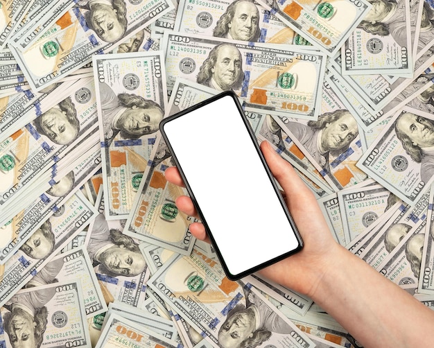 Финансовый макет телефона в руке над кучей долларов Финансовый макет смартфона