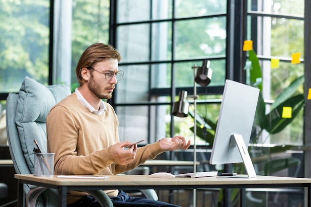 Financial problems a young male businessman is sitting at a desk in the office and looking worriedly