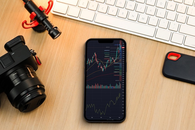 Financial stock market graph on the smartphone screen. Content creator environment with keyboard, camera and mic. Stock Exchange.