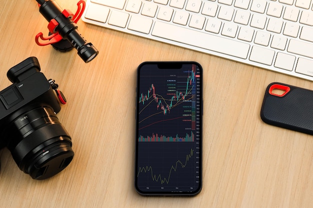 Photo financial stock market graph on the smartphone screen. content creator environment with keyboard, camera and mic. stock exchange.